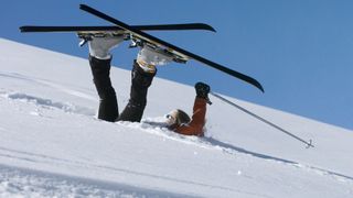 A fall skier with their skis up in the air