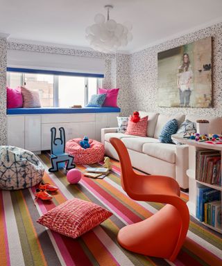 colorful playroom with white sofa, orange chair, striped carpet and built-in bookshelf
