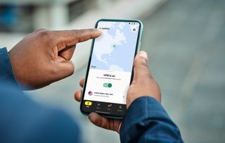 A user touches the screen of a smart phone with the Norton VPN active.
