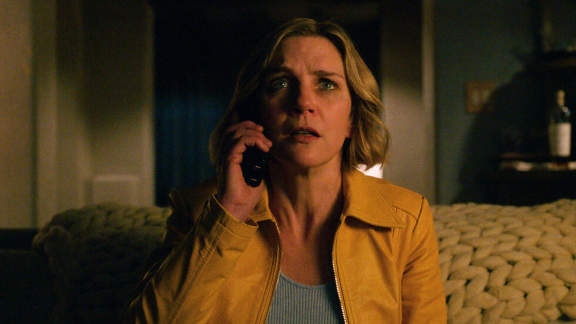 Carol answers her phone in fear while sitting on her couch