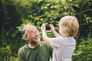 Little boy taking a photo of his Grandpa with a smart phone