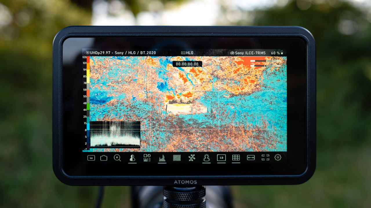 Atomos Shinobi II camera monitor on top of a camera outdoor with green trees in the background