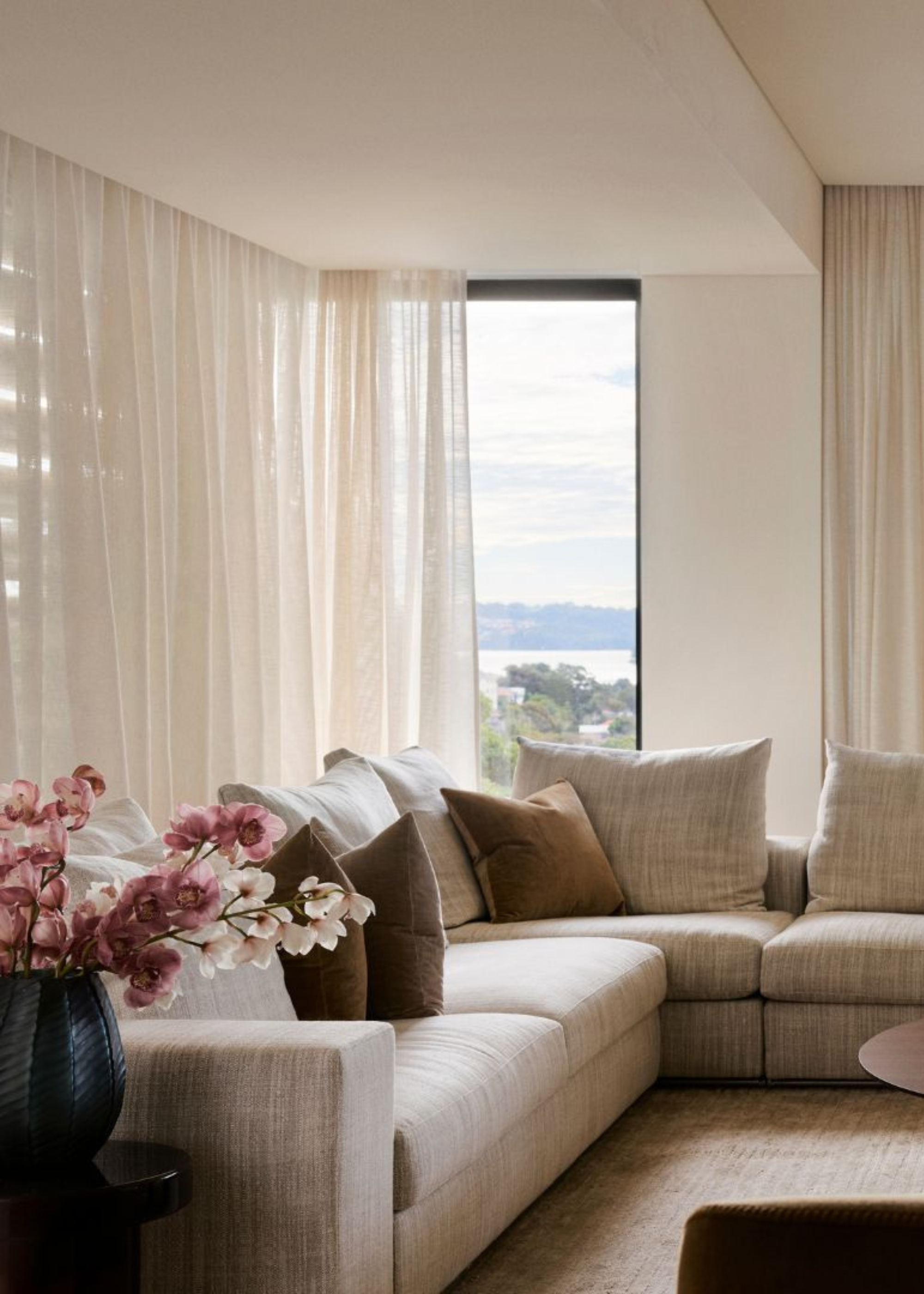 A stylish living room with an L-shaped sofa, a vase of colorful flowers and an attached balcony