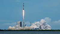 a black-and-white spacex falcon 9 rocket launches into a blue sky.