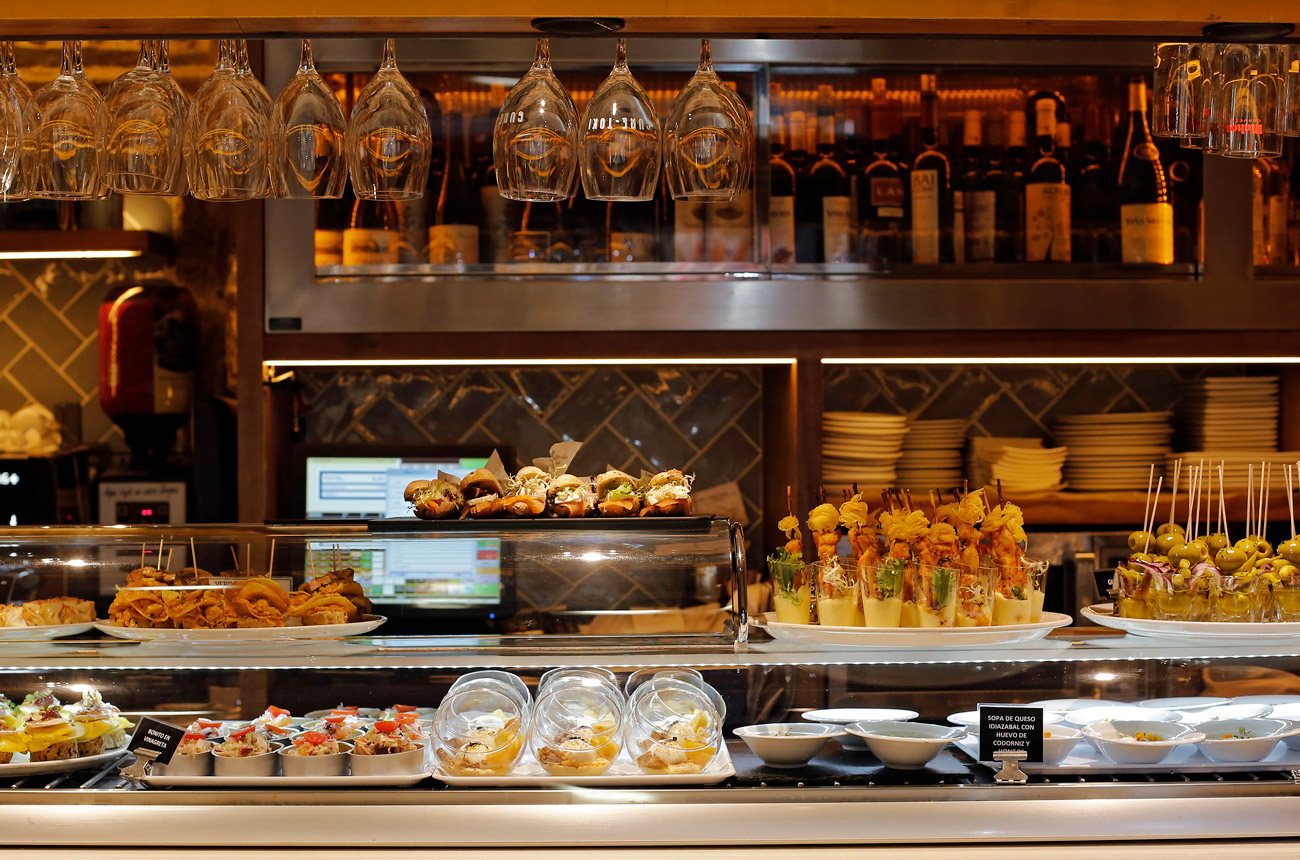 Selection of food on a counter with shelves of bottles of wine behind