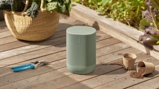 The Sonos Move 2 in Olive sitting in a garden.
