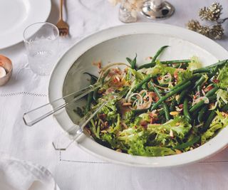 Green Beans And Frisee Salad With Spiced Vinegar And Smoked Almonds, a large white bowl of salad on a table with a white tablecloth.