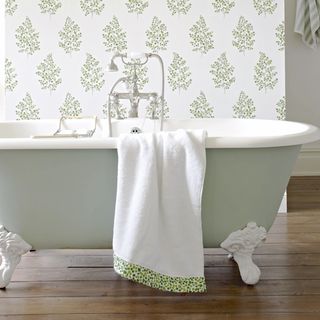 bathroom with leaf printed wallpaper on wall and white bathtub