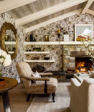 living room with floral patterned textured wallcovering and vaulted ceiling with fire lit