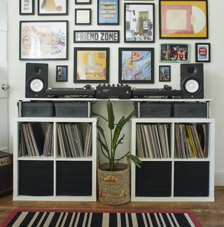 White bookcase containing music records with record player and speakers on top of it