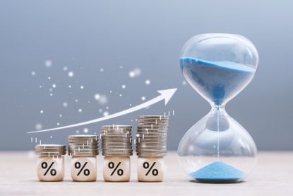 Stacked coins on percentage blocks growing over time with hourglass. Long term investment and compound interest. 