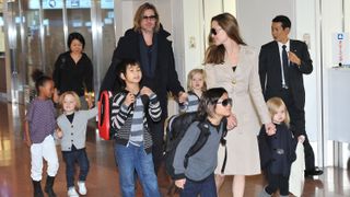 Brad Pitt and Angelina Jolie walk through an airport with their children.
