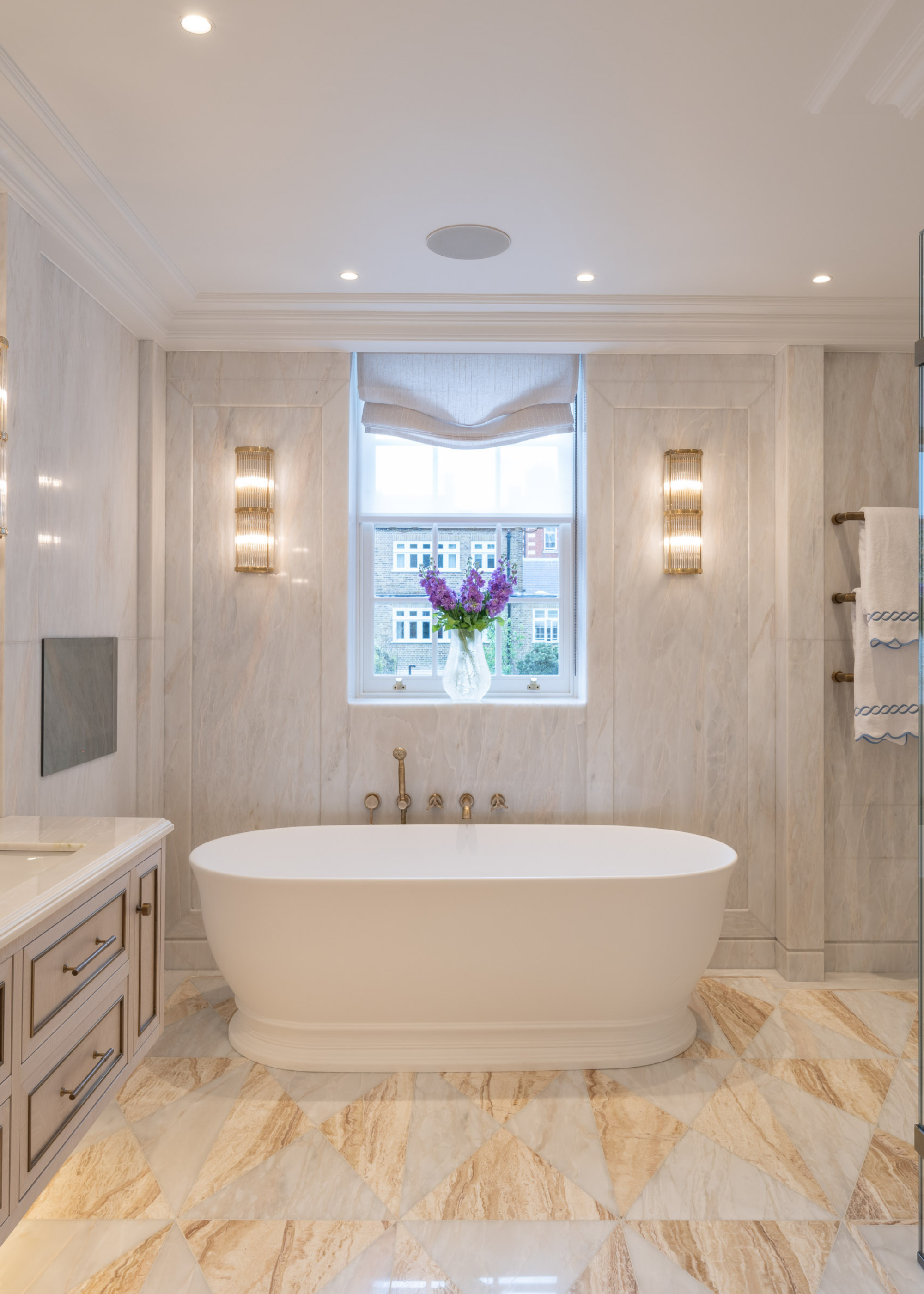 luxurious bathroom with freestanding tub, neutral stone tiles used on the floor, and neutral stone used across the walls