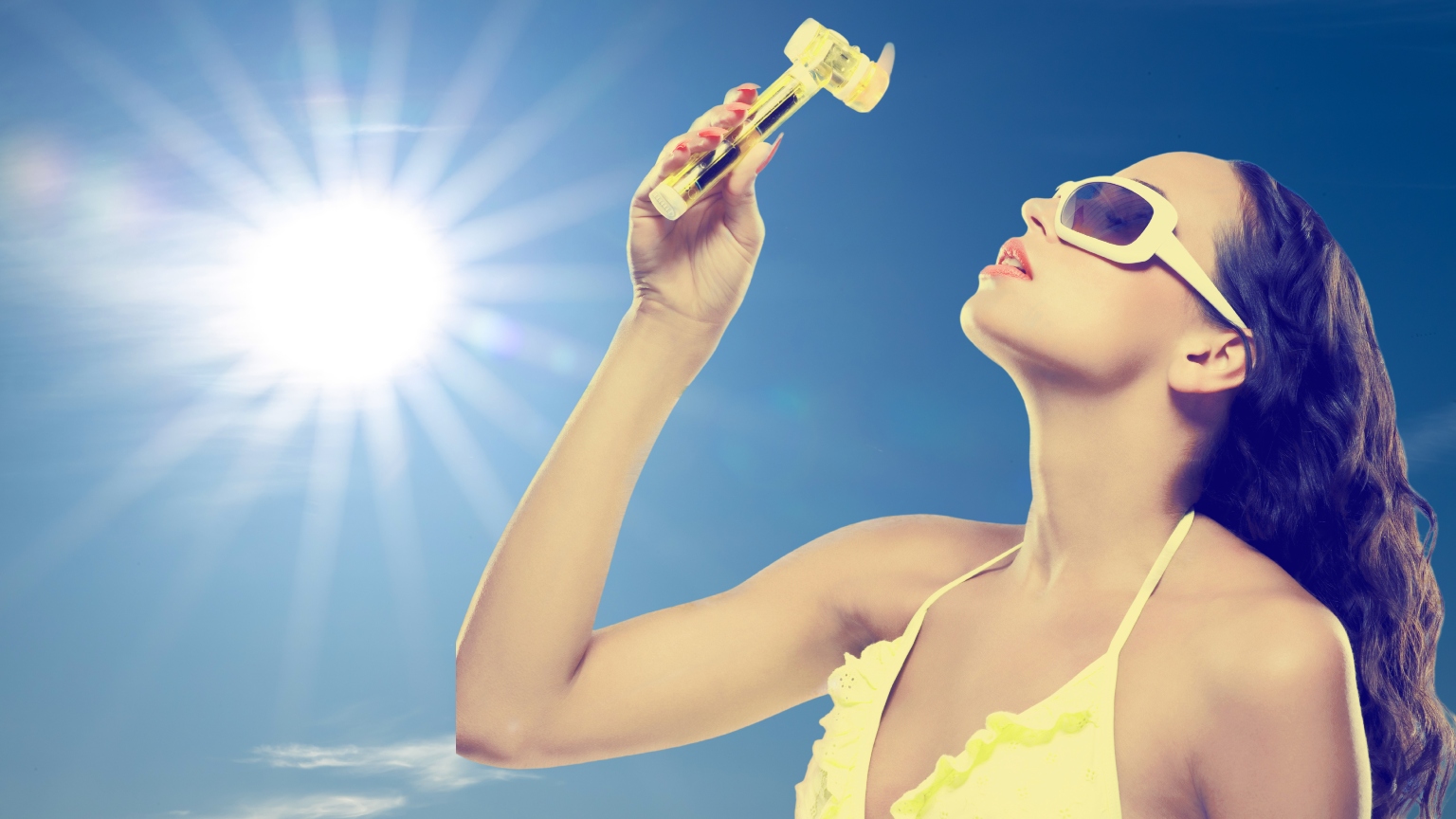 a woman with dark hair in a yellow bikini top holding a yellow fan against the sun and sky background