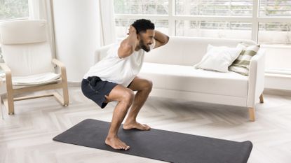 Man doing squat exercise on a yoga mat in pristine living room