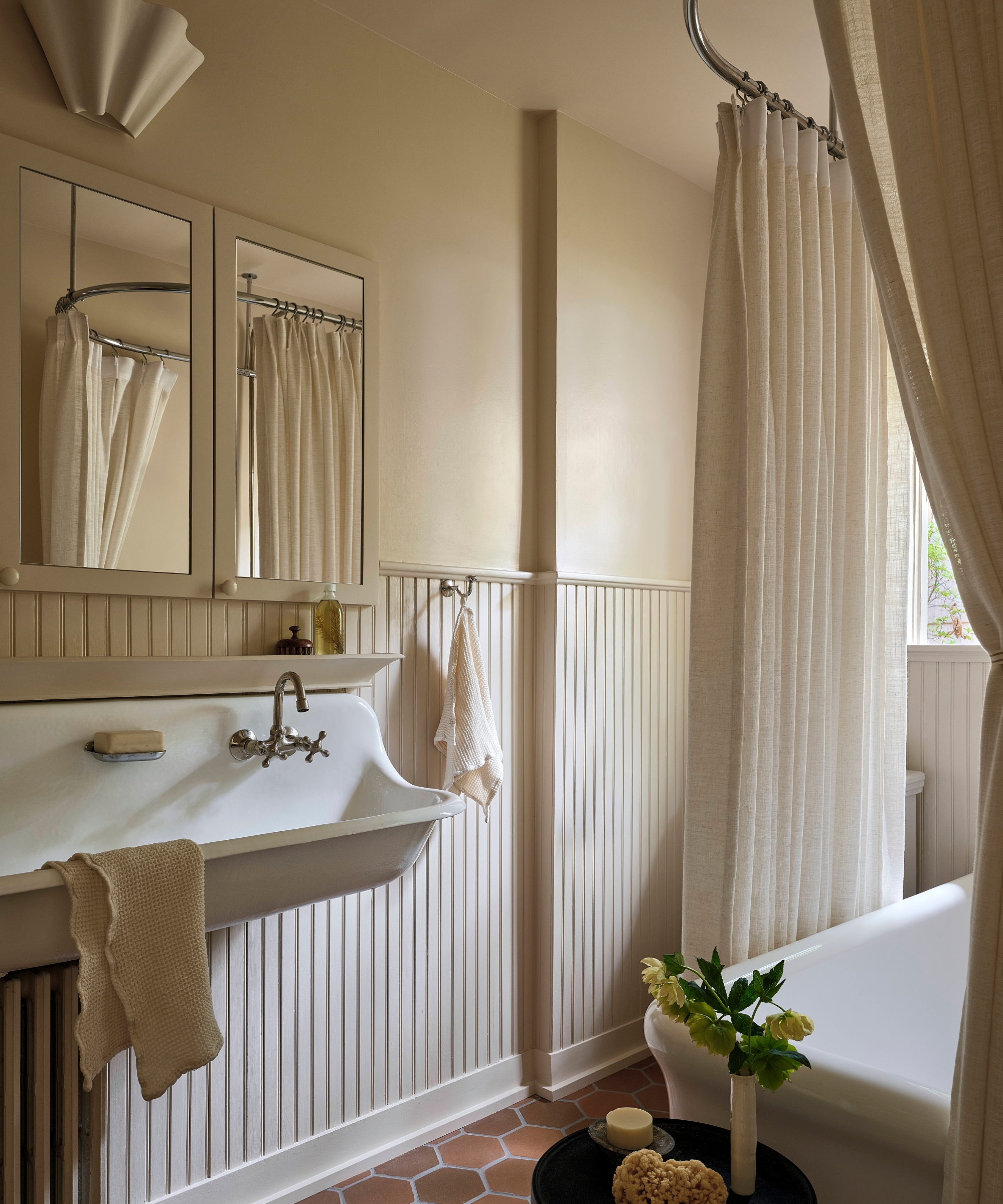 A soft neutral color drenched bathroom with terracotta floors