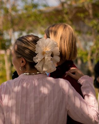 two girls hug at Copenhagen Fashion Week while one wears an extra-large frilly scrunchie