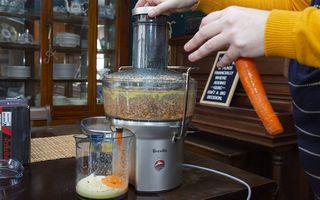 Best juicers: A woman uses a juicer machine to make fresh orange and carrot juice