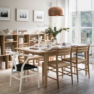 Neutral dining room with wooden furniture and a wall of low open shelving for crockery