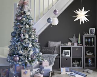 Living room with Christmas tree and storage boxes under stairs with cards displayed on top