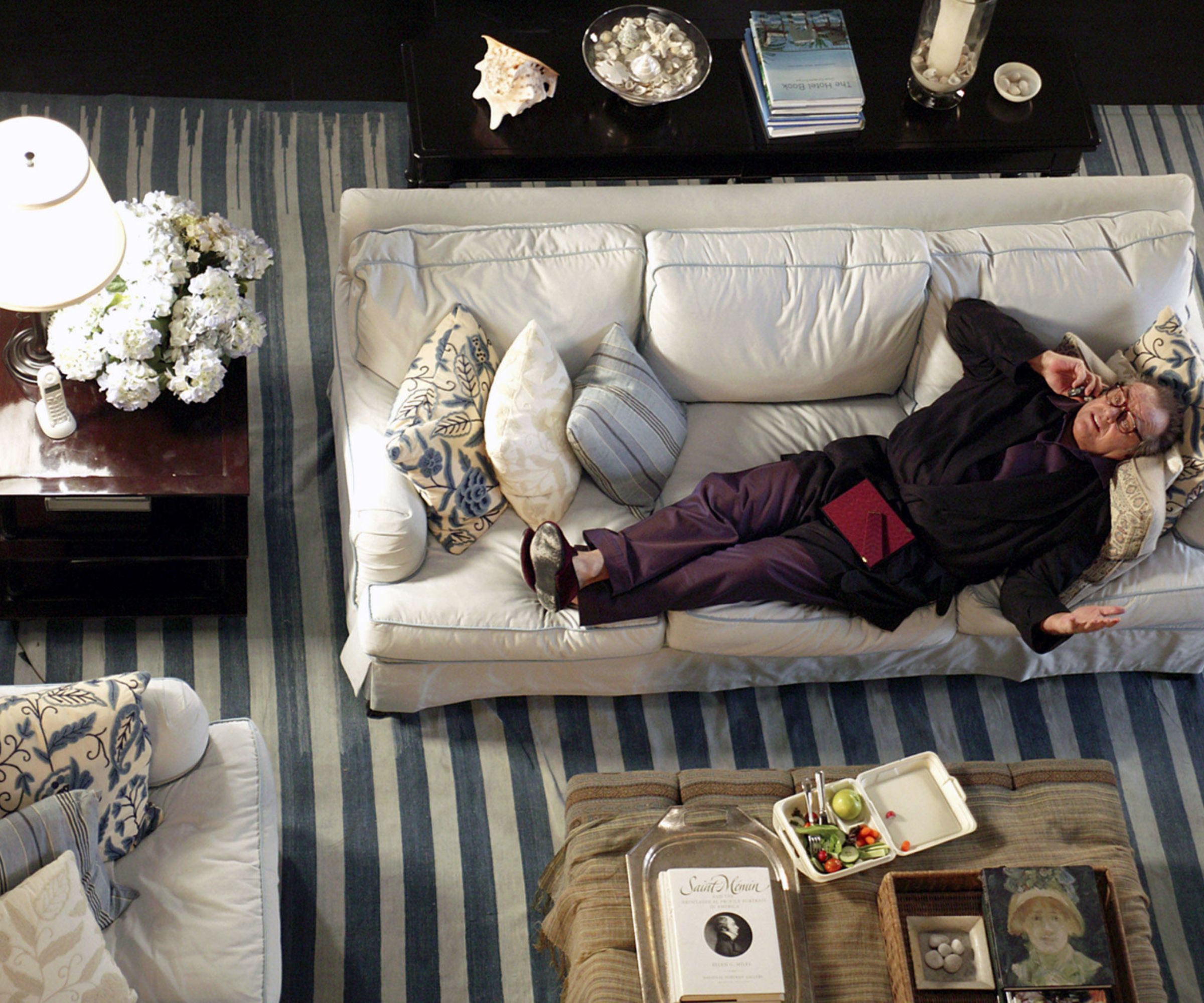 still image from 'Somethings Gotta Give' 2003 movie by nancy meyers showing Jack Nicholson lying on a white linen sofa with a blue stripe carpet underneath, antique furniture and decor and a large hydrangea plant