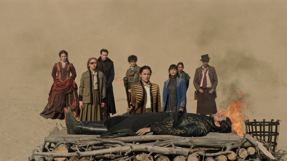 The Shadow and Bone season 2 cast assemble in front of a pyre with The Darkling lying on it in season 2 episode 8.