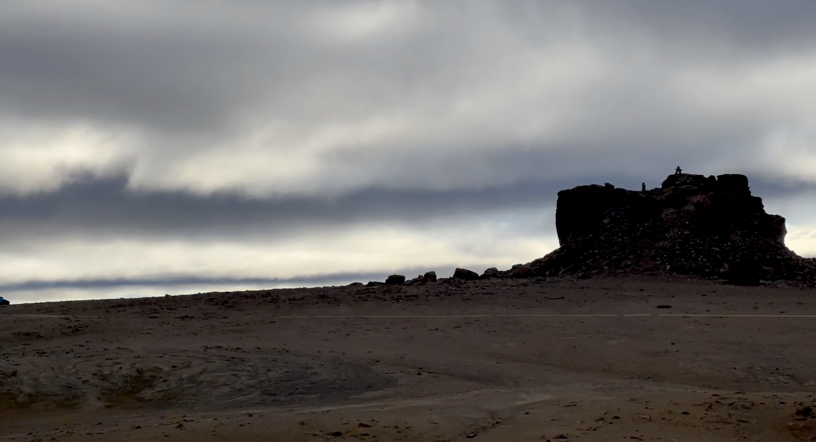 Ominous clouds roll in above a barren Arctic landscape.