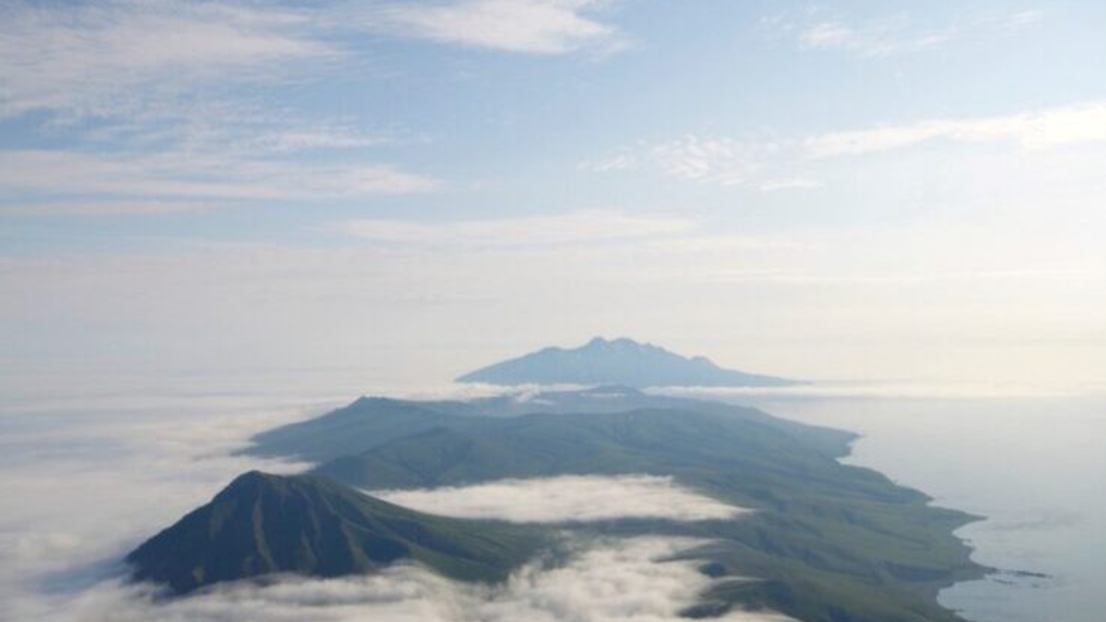 A photo of three of the volcanoes stretched out toward the horizon, taken from the summit of one of the other peaks