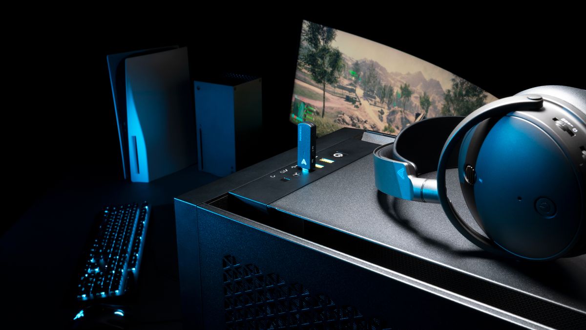 Audeze Maxwell wireless gaming headset for Xbox &amp; PC on top of a gaming desktop, with Xbox Series X, gaming monitor, and PS5 in background.