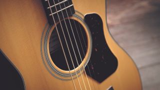 Soundhole, pickguard and upper frets of a spruce-topped Walden acoustic guitar