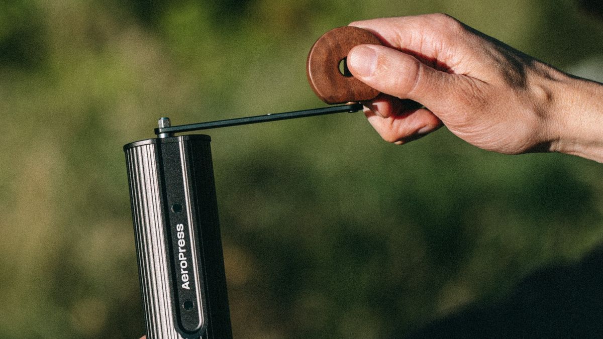 Person using Walnut AeroPress coffee grinder