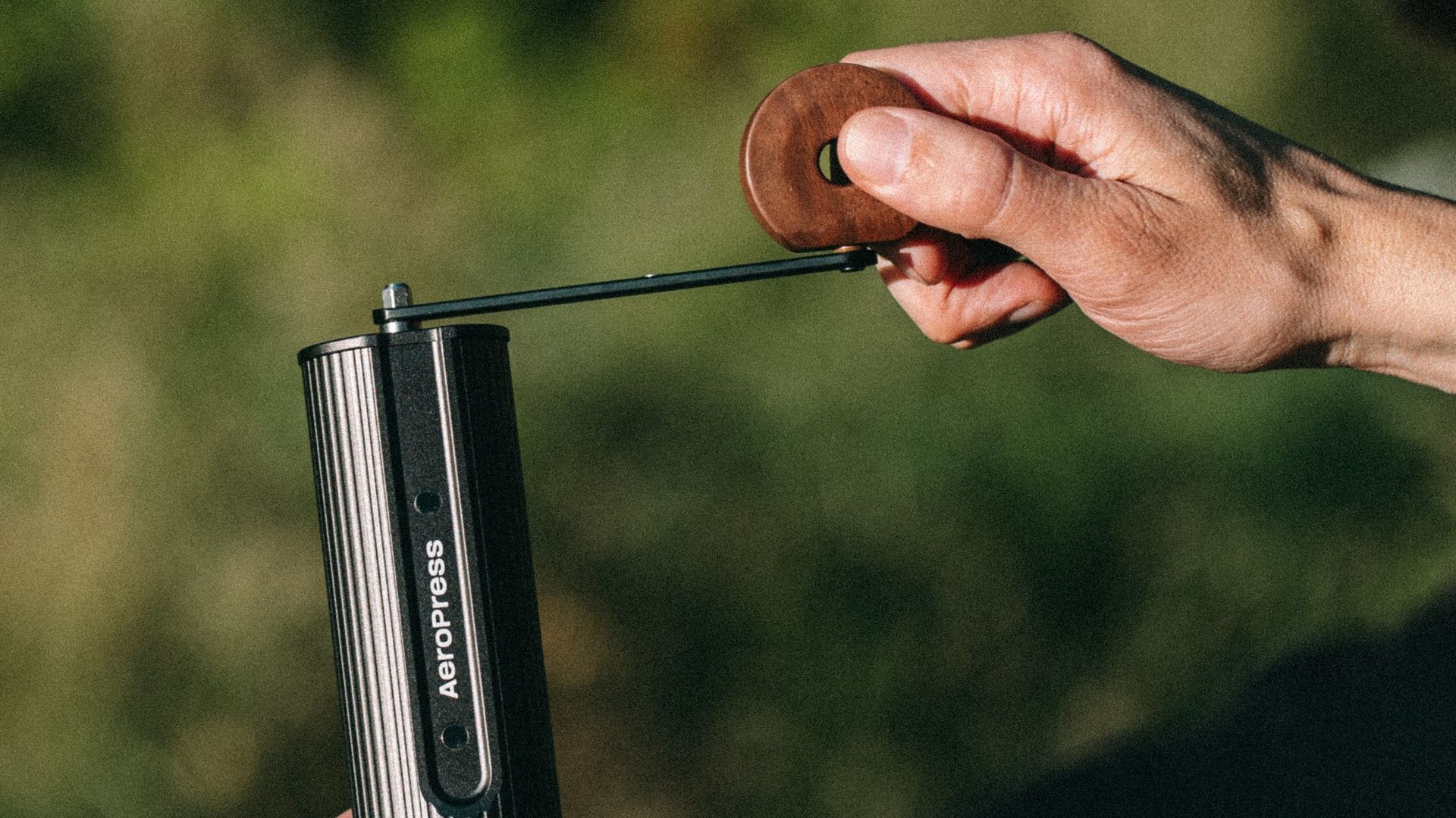 Person using Walnut AeroPress coffee grinder