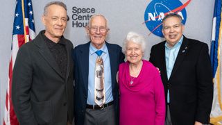 Tom Hanks with poses for a photo with an Apollo astronaut and his wife, as well as a museum director