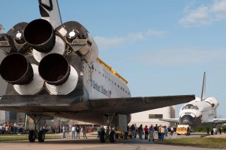 Space shuttle Atlantis (foreground) faces its younger sister, space shuttle Endeavour as the latter leaves the Orbiter Processing Facility for the last time at NASA’s Kennedy Space Center in Florida on Aug. 16, 2012.