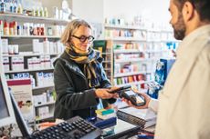 An older woman purchases drugs at the pharmacy counter.