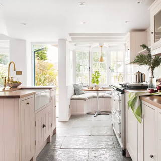 Pale pink kitchen cabinets in light kitchen with bay window