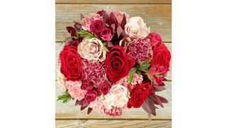 A Bouqs flower arrangement of pink and red roses and carnations from overhead, for the best flower delivery services.
