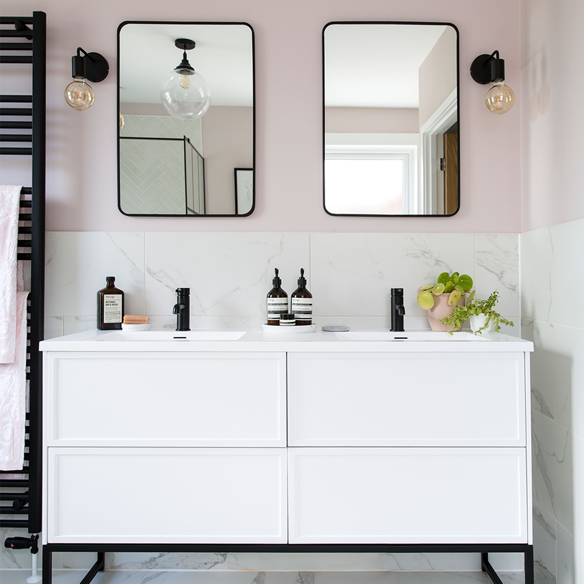 Pink bathroom with white double vanity unit and black mirrors