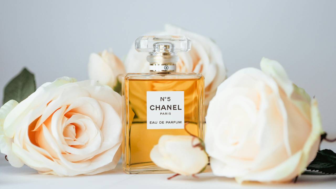 A bottle of Chanel No.5 surrounded by white roses