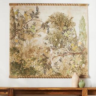 A landscape-based tapestry hanging on a white wall above a wooden console table