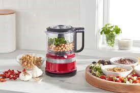 A KitchenAid food processor filled with fresh produce on a kitchen countertop