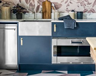 blue kitchen cabinetry with patterned wall and stainless steel sink and appliances