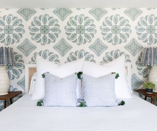 double bed with with blue patterned wallcovering behind