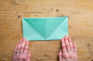 A folded piece of green paper on a wooden table