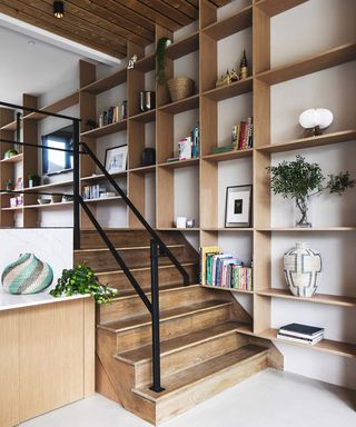A wooden staircase with black staircase railing and wooden fitted shelf