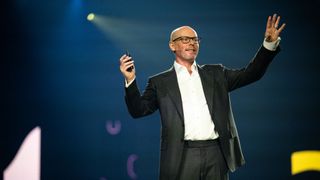 Oracle NetSuite executive vice president Evan Goldberg, delivering a keynote address with his hands raised 