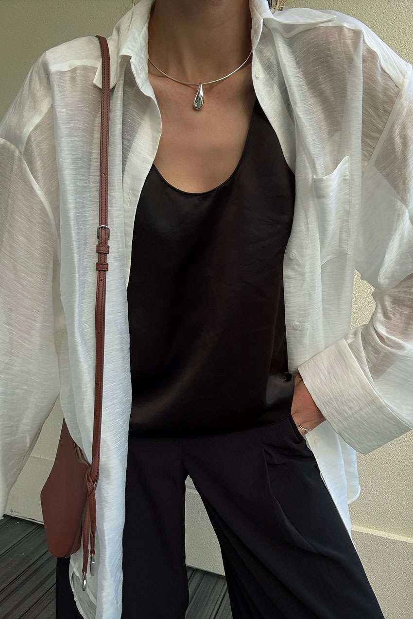a woman wearing a white button-down, black tank top, and black pants