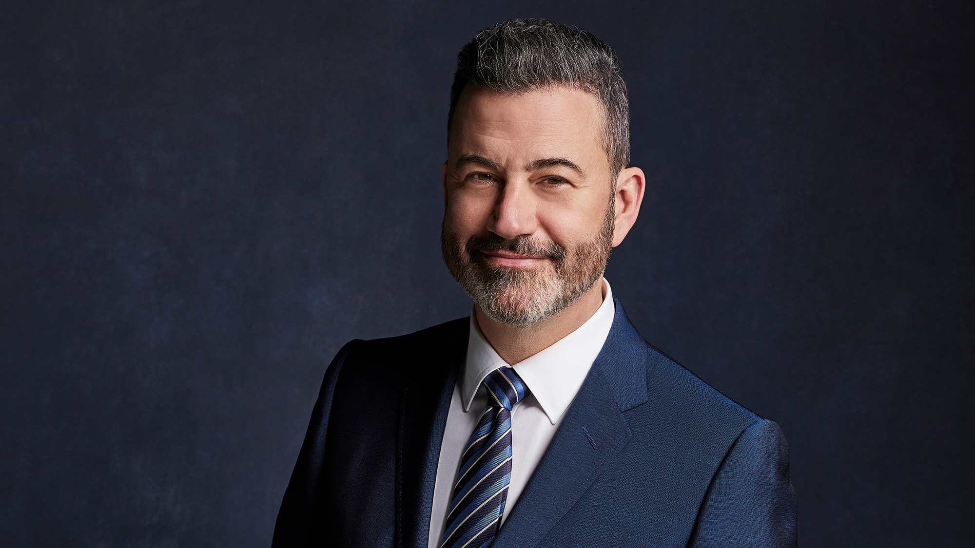 Jimmy Kimmel Live press photo ahead of 2026 fall TV season. He is wearing a blue suit and tie.