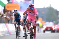 Isaac Del Toro tips in helmet as he crosses the stage 20 finish line at Sestriere
