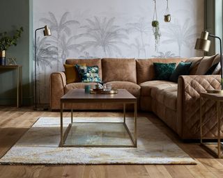 A green and white living room corner idea with brown leather sofa, palm-print wallpaper decor and rug